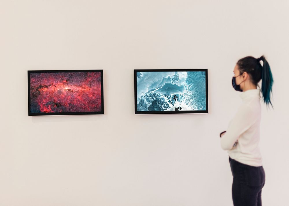 Girl looking at digital frames on a white gallery wall