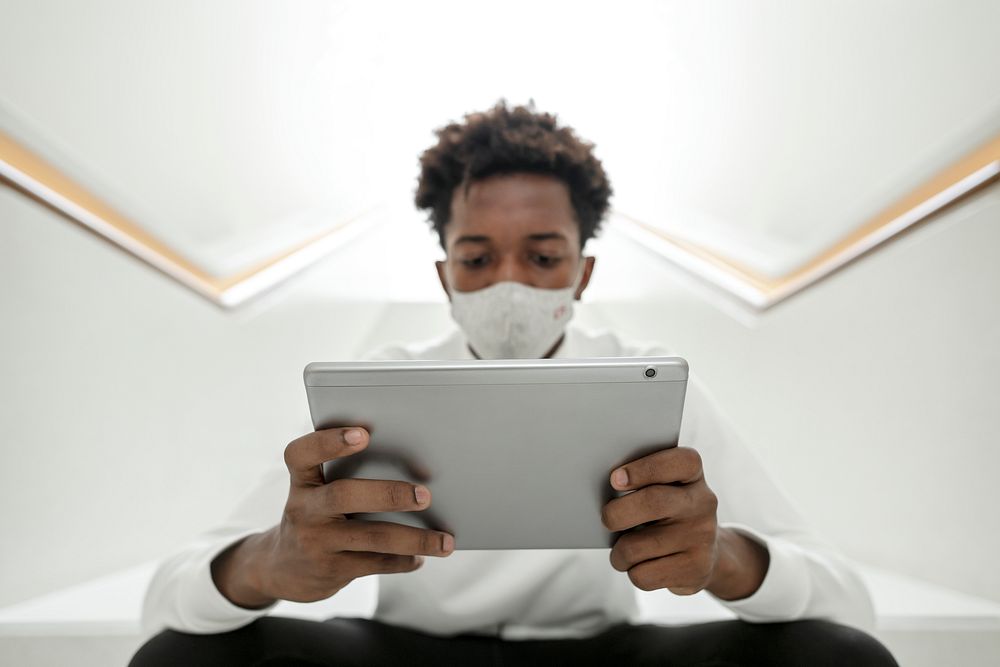 Man with face mask using digital tablet smart technology