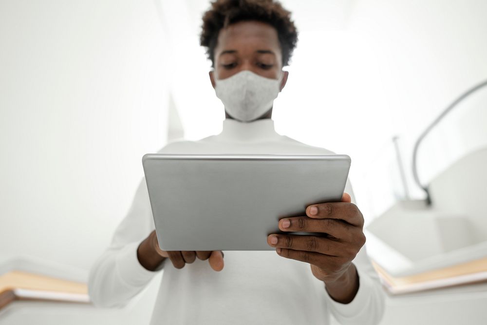 Man with face mask using digital tablet smart technology