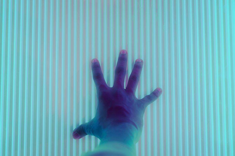 Hand touching an interactive neon screen
