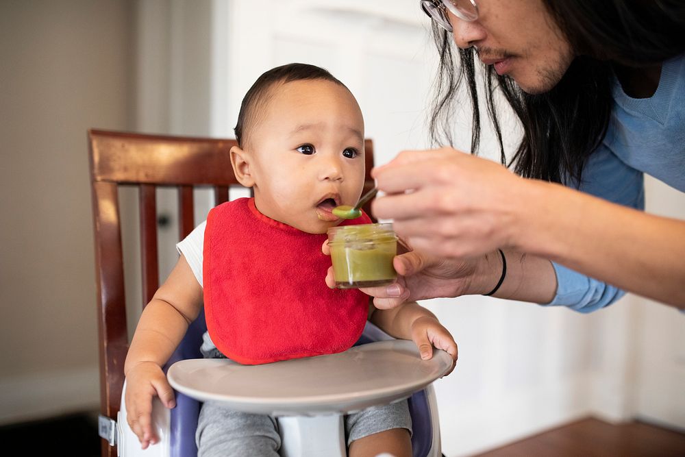 Asian father feeding his son with baby puree