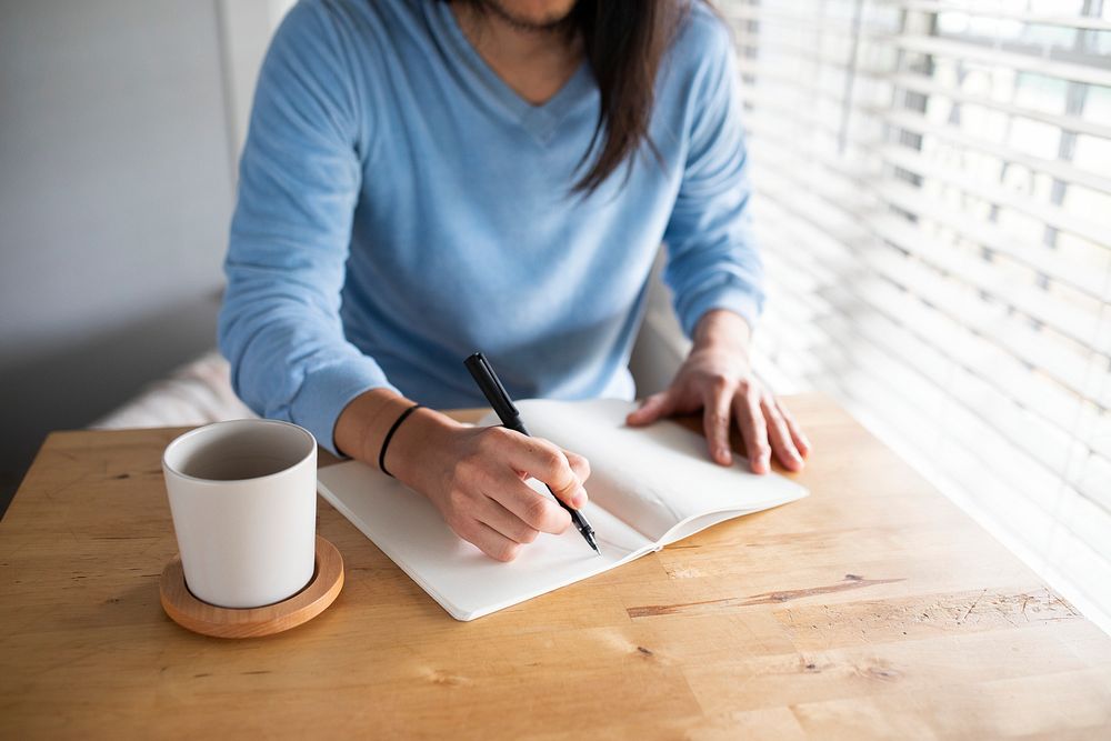 Man writing in a journal while at home in the new normal