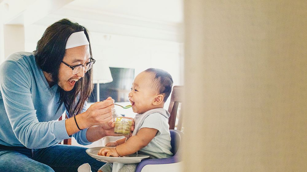 Asian father feeding his son with baby puree