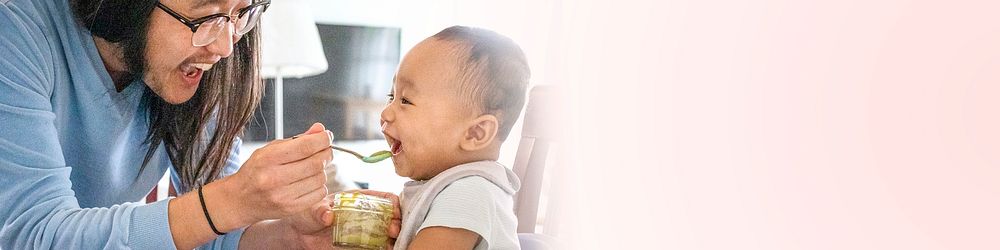 Asian father feeding his baby boy with food puree social banner