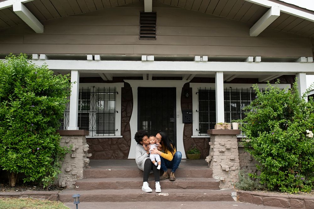 Happy multiracial parents kissing their son in front of the house during covid19 lockdown