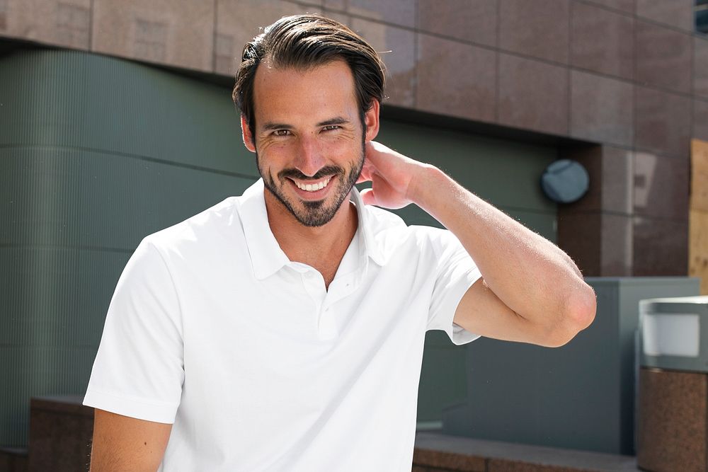 Handsome man smiling in white polo shirt city portrait