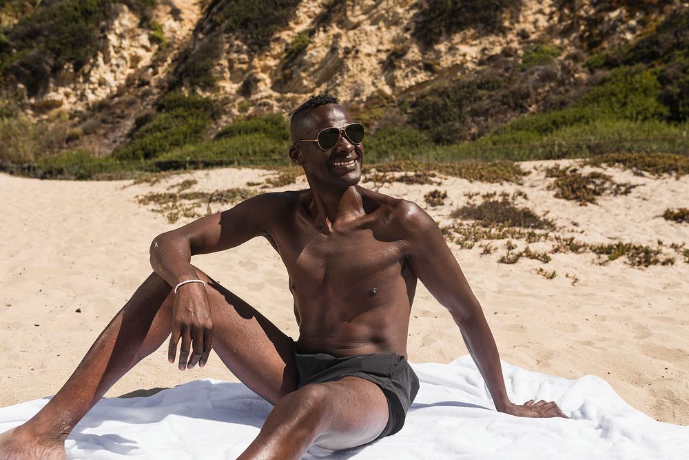Happy African American chilling at the beach on his vacation