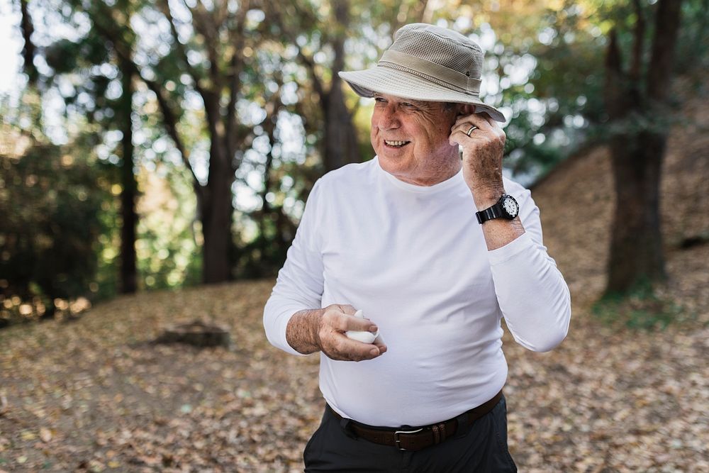 Retired man enjoying music in the middle of the forest 