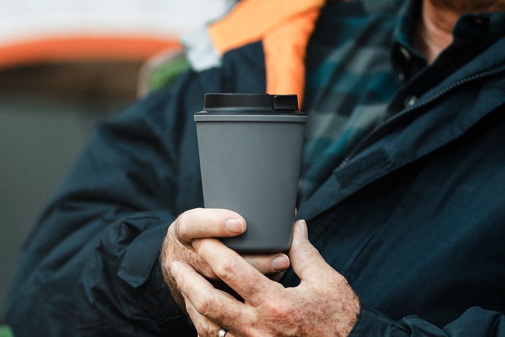 Senior man holding gray reusable travel cup