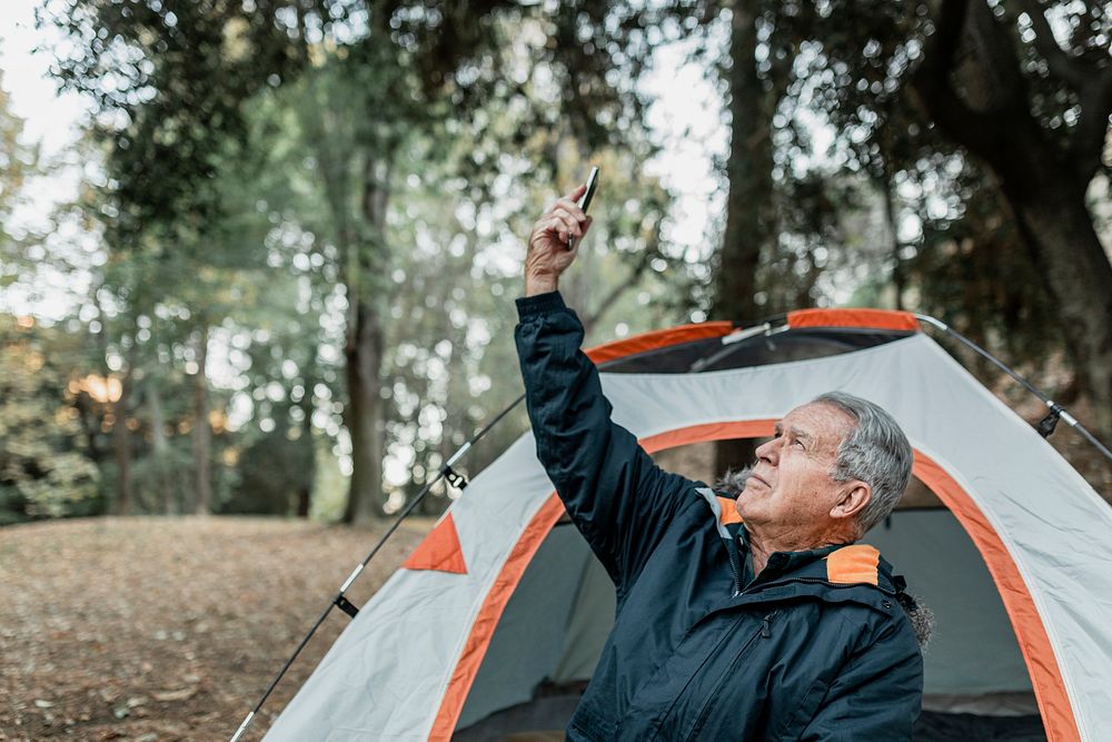 Elderly man searching for internet connection in the forest 