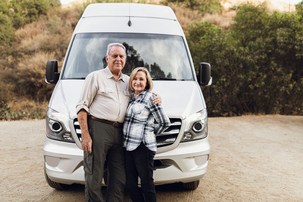 Happy senior couple standing in front of motorhome