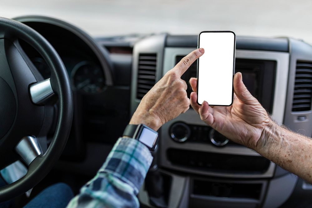 Grandpa showing his smartphone to grandma while driving