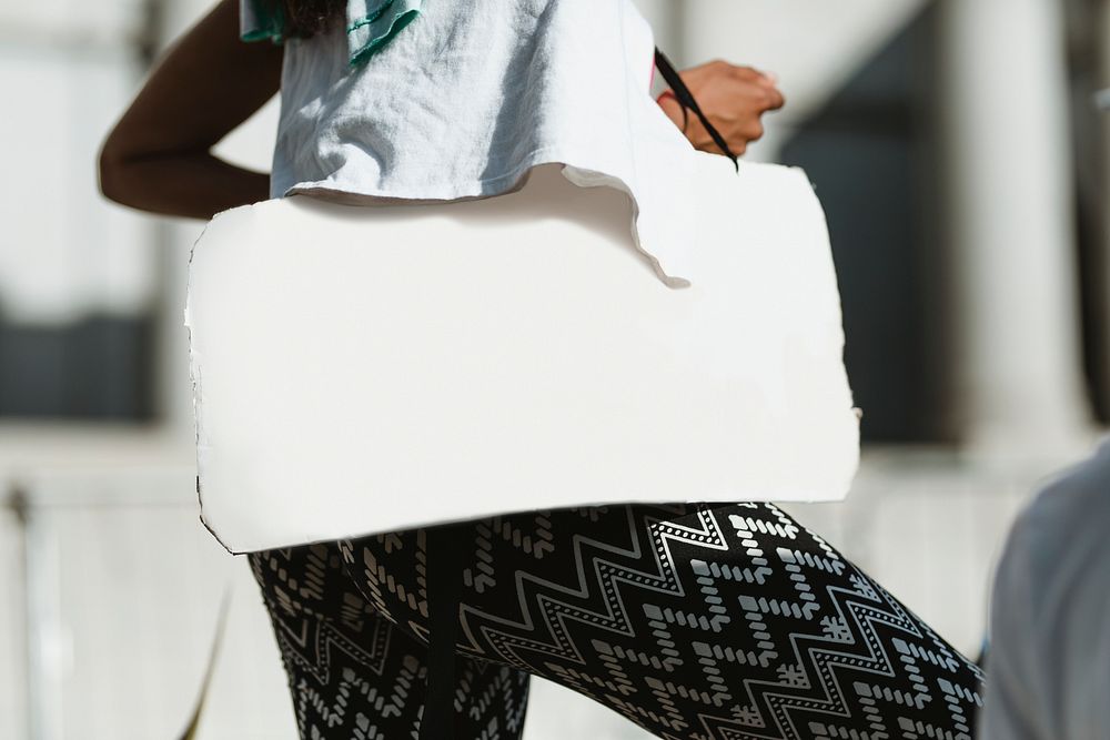 Black woman carrying a white placard with copy space 