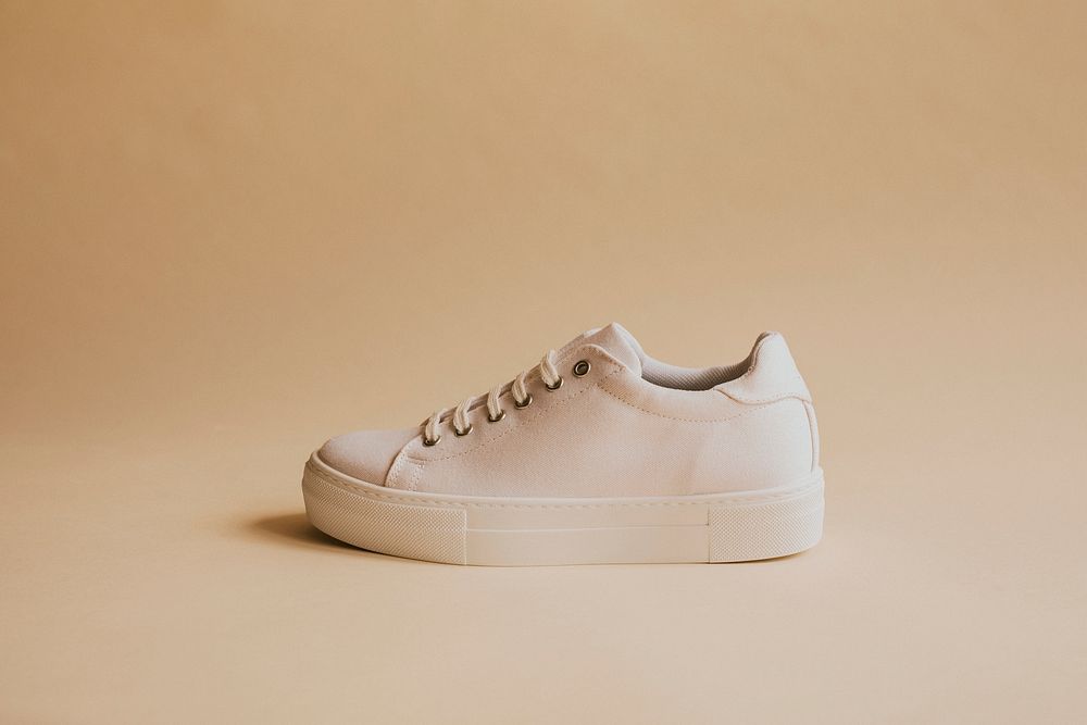 Single white canvas sneakers on beige