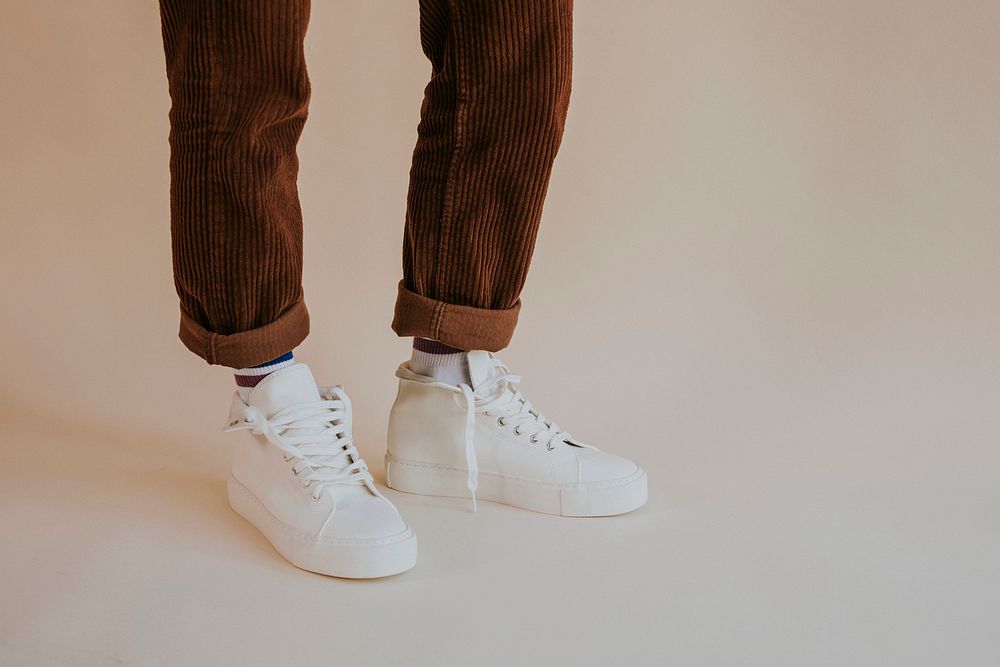 White canvas sneakers with untied laces on model
