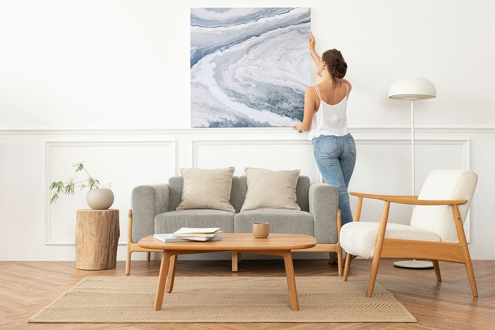 Woman arranging frame on a wall in a Scandinavian living room