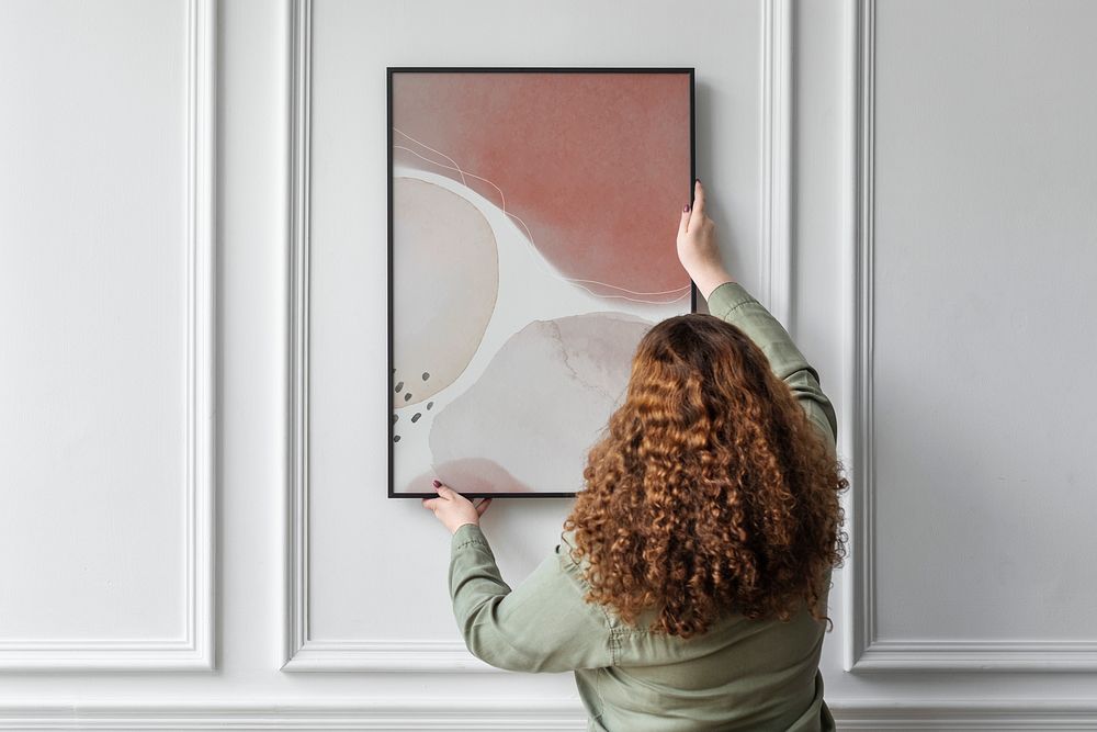 Woman hanging picture frame on the wall with design space