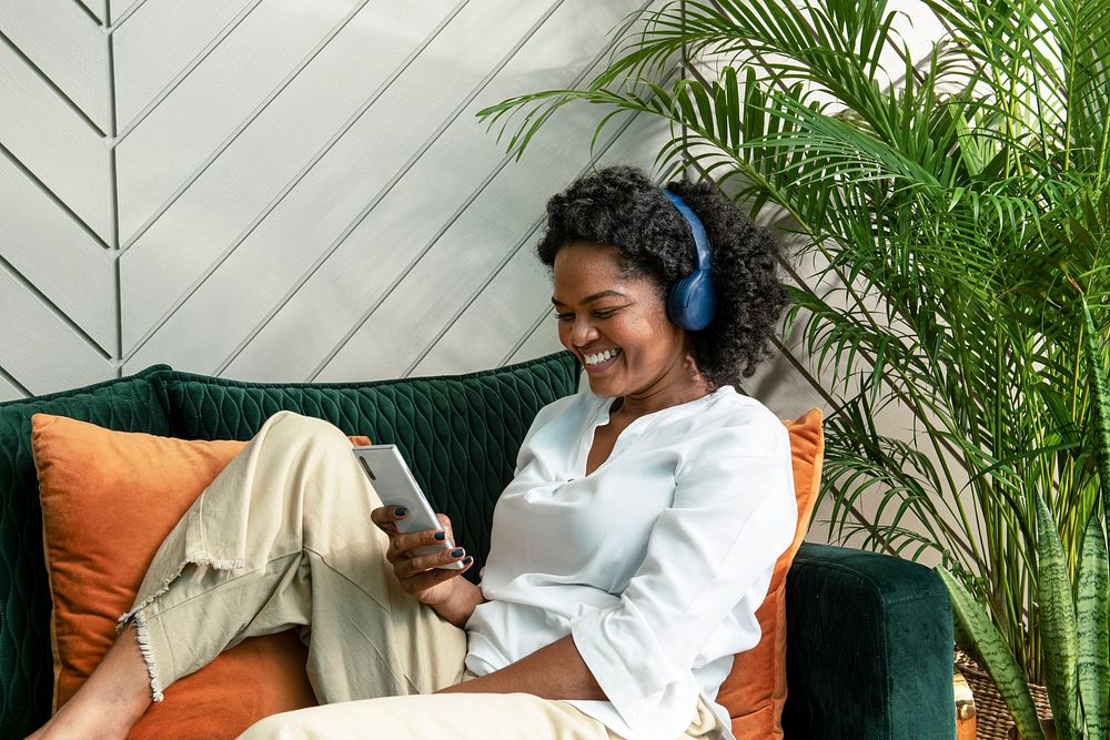 Cheerful woman listening to music through headphones at home