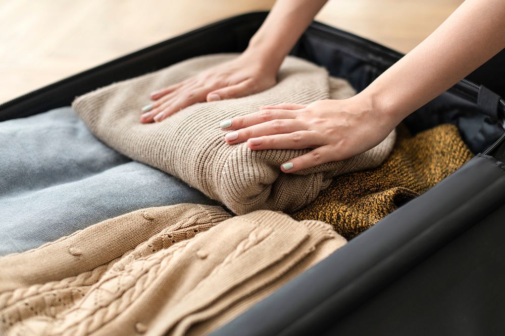 Wife packing her winter clothes in a luggage for a trip