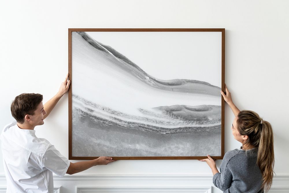 Abstract painting being hung by a couple