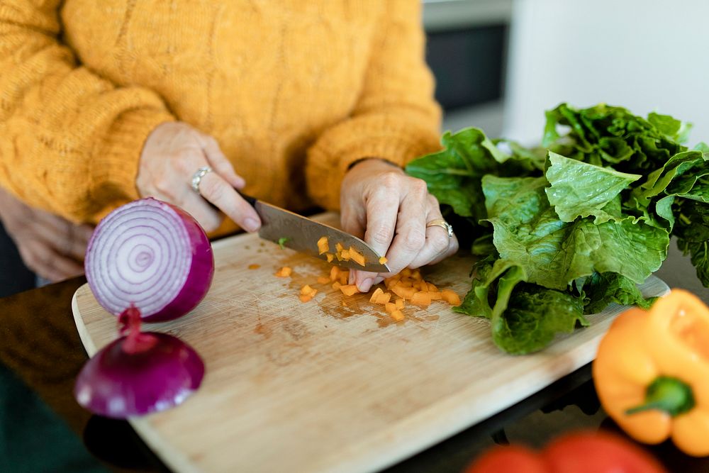 Woman slicing bell pepper and cooking in a kitchen