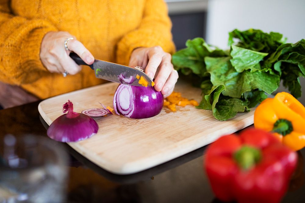Woman slicing red onion and cooking in a kitchen
