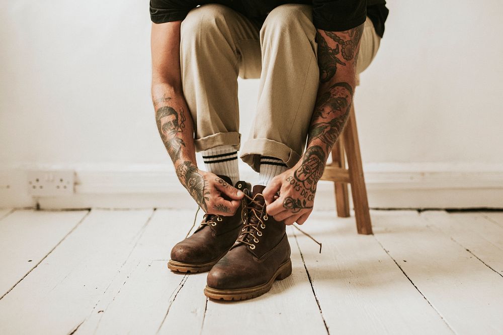 Alternative man tying boots shoelaces on the floor