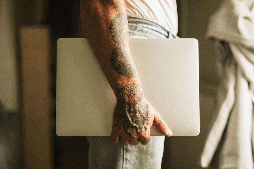 Tattooed alternative man carrying a laptop