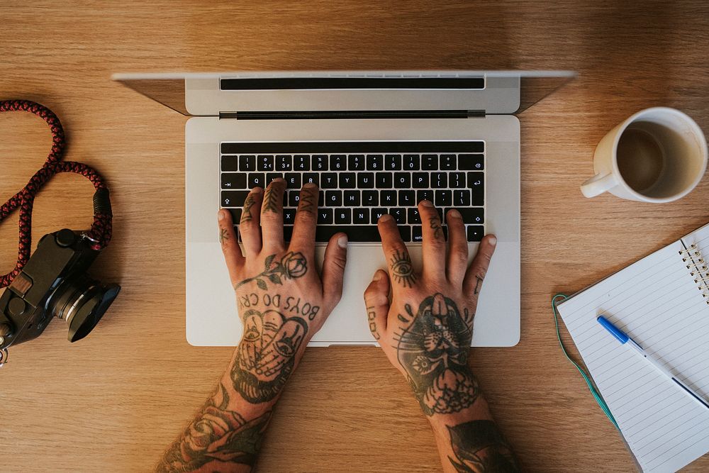 Alternative tattooed man working on laptop