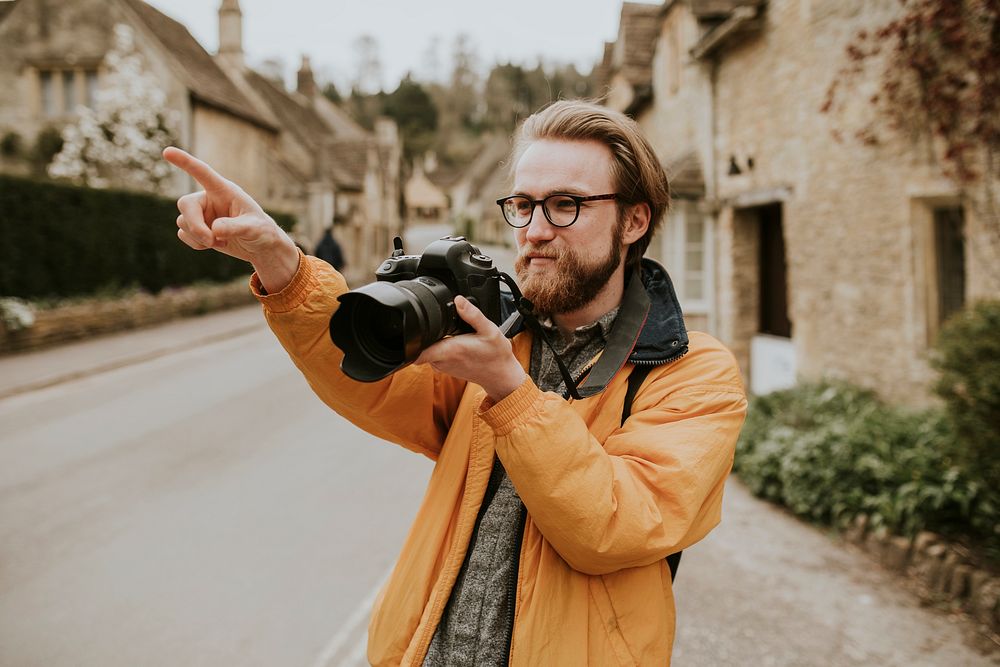 Photographer man pointing in the village in Cotswolds, UK