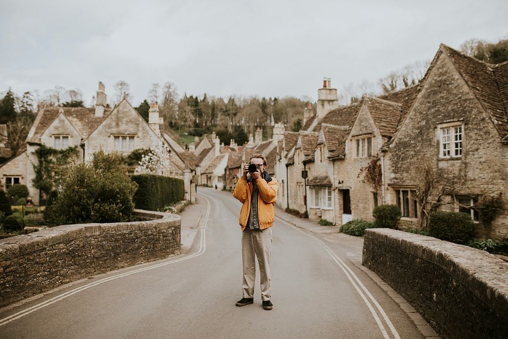 Photographer man taking photos in the village Cotswolds, UK