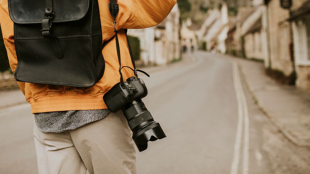 DSLR camera with strap hanging on photographer&rsquo;s shoulder