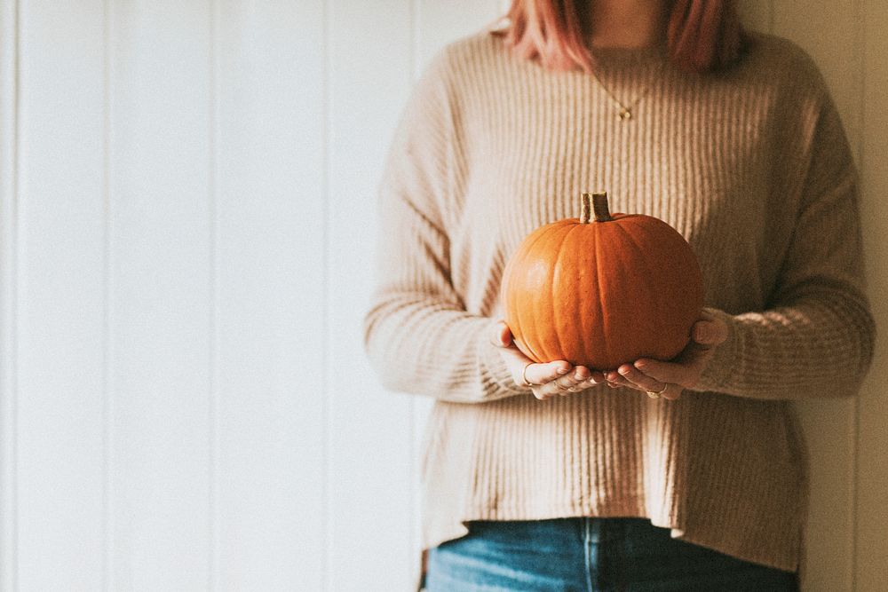 Woman holding Halloween pumpkin in a farmhouse autumnal mood