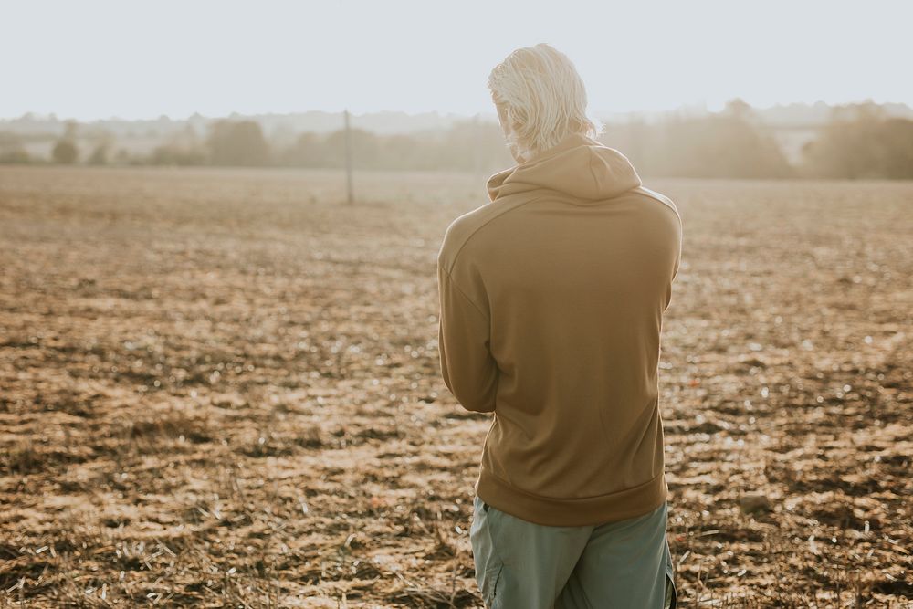 Man in stretchy hoodie in the countryside at sunset