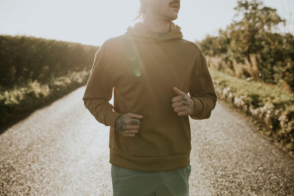 Man in stretchy hoodie jogging in the countryside at sunset