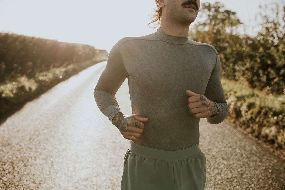 Man in stretch shirt running in the countryside at sunset
