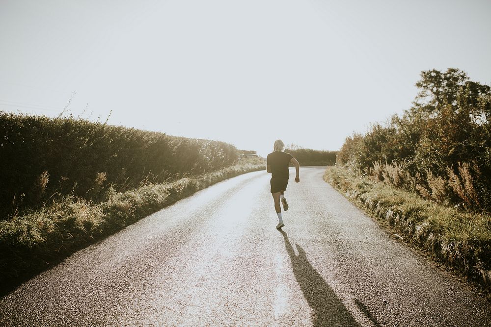 Man running in the countryside at sunset rear view