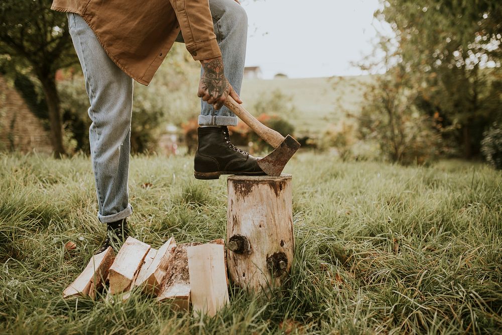 Country man splitting wood with axe on the field