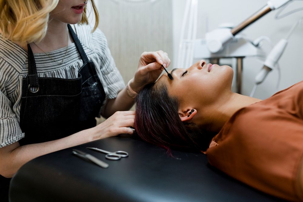 Beautician giving eyebrow treatment to a customer at a beauty salon