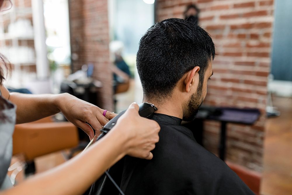 Man getting a haircut from a hair stylist at a barber shop 