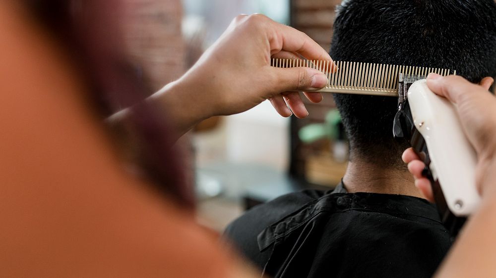 Hairdresser trimming hair of the customer at a barbershop 