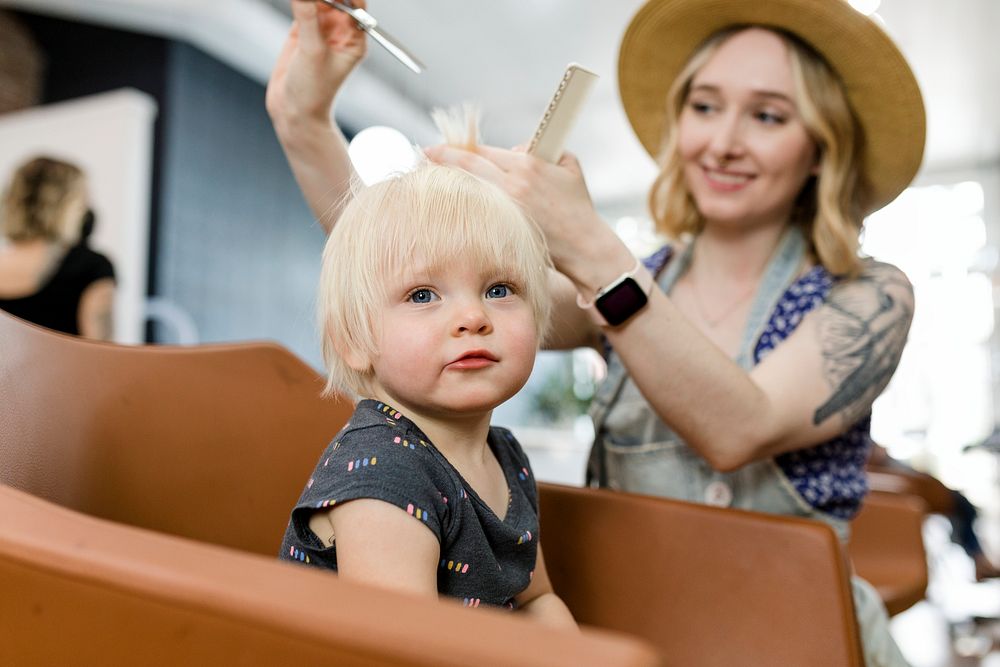 Hairstylist giving a little kid a haircut 