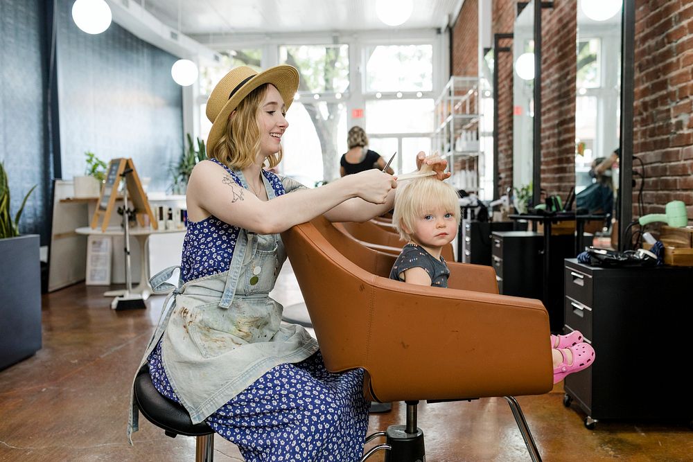 Hairstylist giving a haircut to an adorable blond kid 