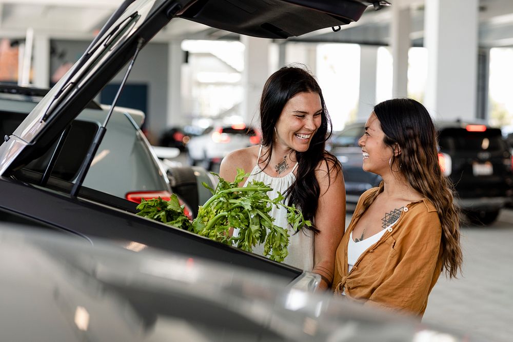 Lesbian couple grocery shopping, putting stuff in car trunk