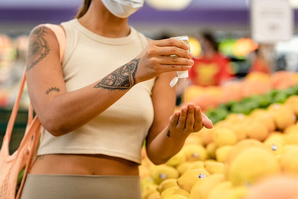 Woman using hand sanitizer, grocery shopping image
