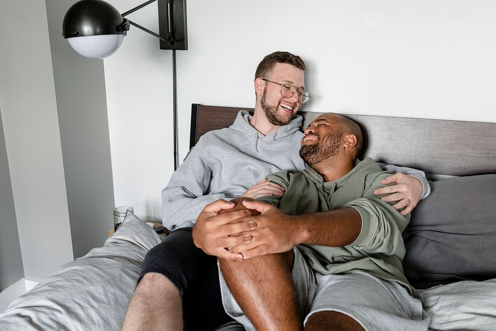 Happy gay couple image, cuddling on bed