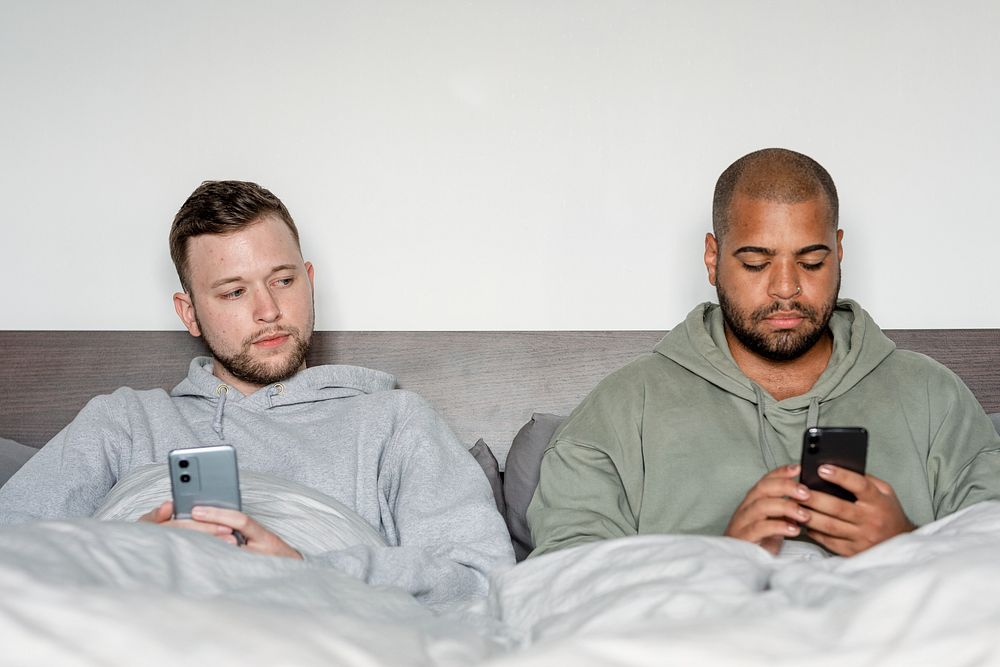 Angry gay couple image, on their phones after arguing