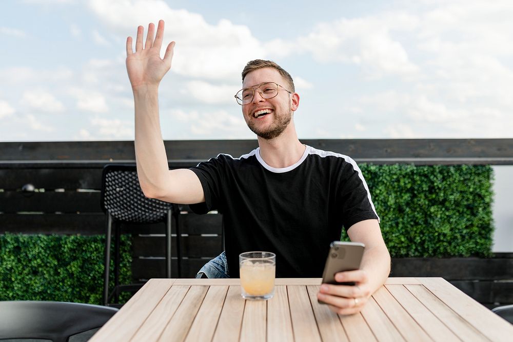 Man waving to friend while sitting in a cafe