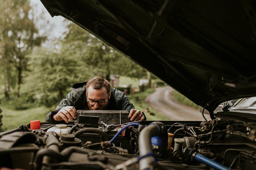 Man repairing a car engine outdoors