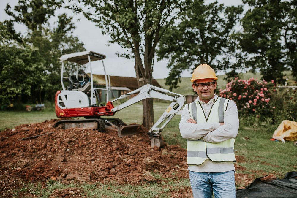 Civil engineer standing by an excavator outdoors 